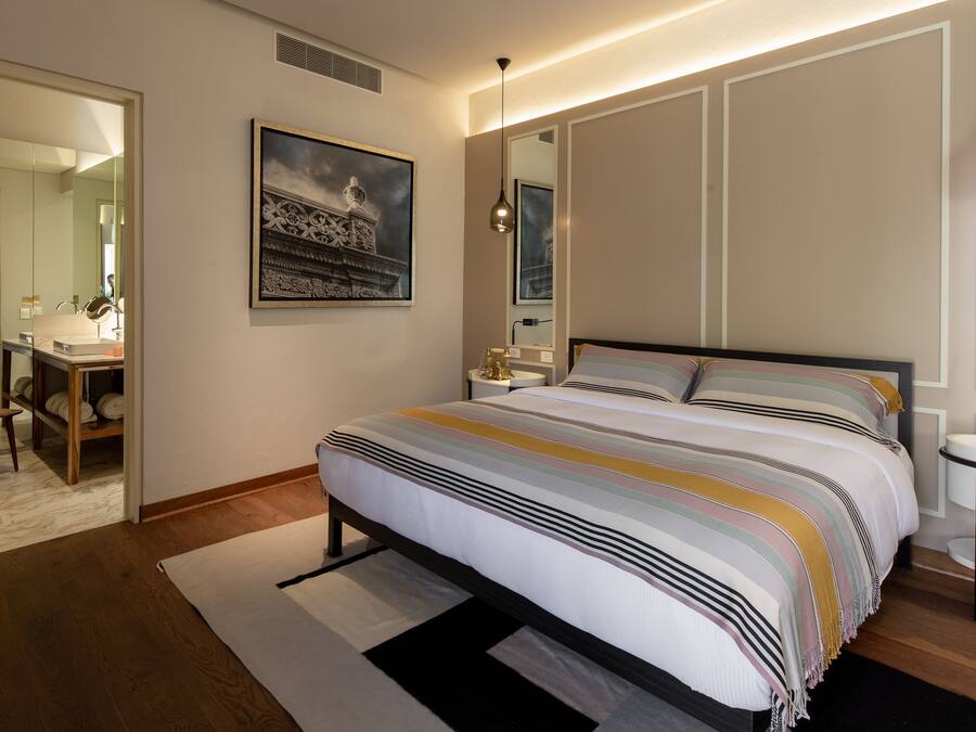 Un dormitorio moderno con una cama grande, mesitas de noche, un espejo y un cuadro en la pared.