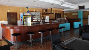 Una zona de bar con mostrador, taburetes y refrigerador.