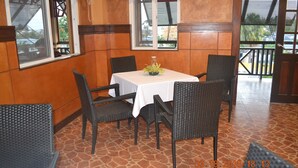 Un comedor con una mesa y cuatro sillas, una ventana con persianas y vistas al exterior.