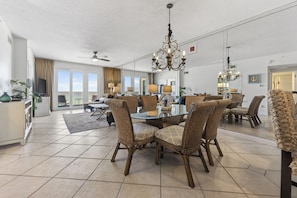 A spacious living room with a dining area, large windows, and a ceiling fan. - Inn at Crystal Beach 410 * Gulf Front with Beach Chair Set. Onsite dining! (Destin)