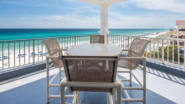 Ein Balkon mit Tisch und Stühlen mit Blick auf einen Strand.