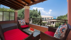 A balcony with wicker furniture, red cushions, and a glass table with a watermelon slice. - Four seasons House (Corfu)