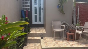 Un patio con una puerta, escalones, sillas y plantas en macetas.
