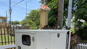 Un generador estacionario con panel de control, ubicado sobre una plataforma de concreto al aire libre.