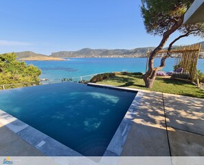 A swimming pool with a view of the sea and a distant town. - Villa PortoMare, PortoRafti Greece (Porto Rafti)