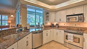 A modern kitchen with granite countertops, stainless steel appliances, and white cabinetry. - < 1 Mi to Beach w/ Pool & Lanai: Marco Island Home (Marco Island)