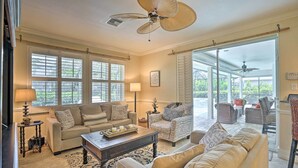 A spacious living room with a large ceiling fan, a sofa set, a coffee table, and a view of the outdoor patio area. - < 1 Mi to Beach w/ Pool & Lanai: Marco Island Home (Marco Island)