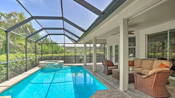 A covered outdoor swimming pool with a hot tub, wicker furniture, and a view of lush greenery. - < 1 Mi to Beach w/ Pool & Lanai: Marco Island Home (Marco Island)