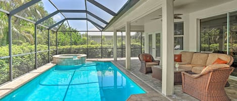 Piscina exterior techada con jacuzzi, mobiliario de mimbre y vista a vegetación exuberante.