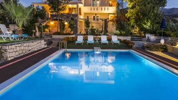 Een buitenzwembad, ligstoelen bij het zwembad