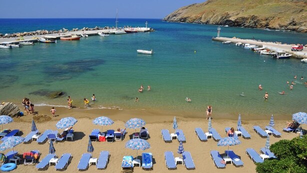 A beach with clear blue water, a rocky coastline, and a pier with boats. - Villa Elisa, View+Hidden in Trees! (Perama)