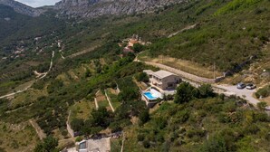 Une propriété située sur une colline, dotée d’une piscine, d’un mur en pierre et d’un chemin qui monte jusqu’au sommet.