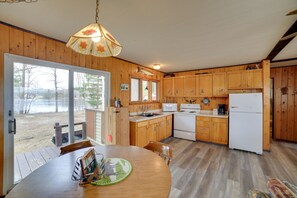 Una cocina con armarios de madera, un refrigerador blanco y una mesa de comedor con sillas.
