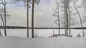 Lumipeitteinen maisema, jossa on puinen terassi ja valaisinpylväs.