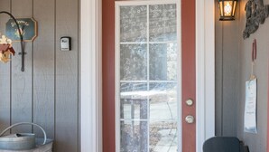 A front door with a frosted glass panel, a welcome sign, a metal bucket, a doormat, and a small statue. - Charming Victorian Farmhouse, Privacy, Wi-FI , 5 min to Durango (Durango)