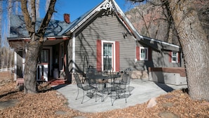 A house with a porch, a table with chairs, and a garage. - Charming Victorian Farmhouse, Privacy, Wi-FI , 5 min to Durango (Durango)