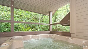 Un jacuzzi con vistas a exuberante vegetación a través de amplios ventanales.