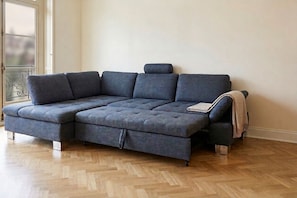 A sectional sofa with a chaise, positioned in a room with wooden flooring and a window.