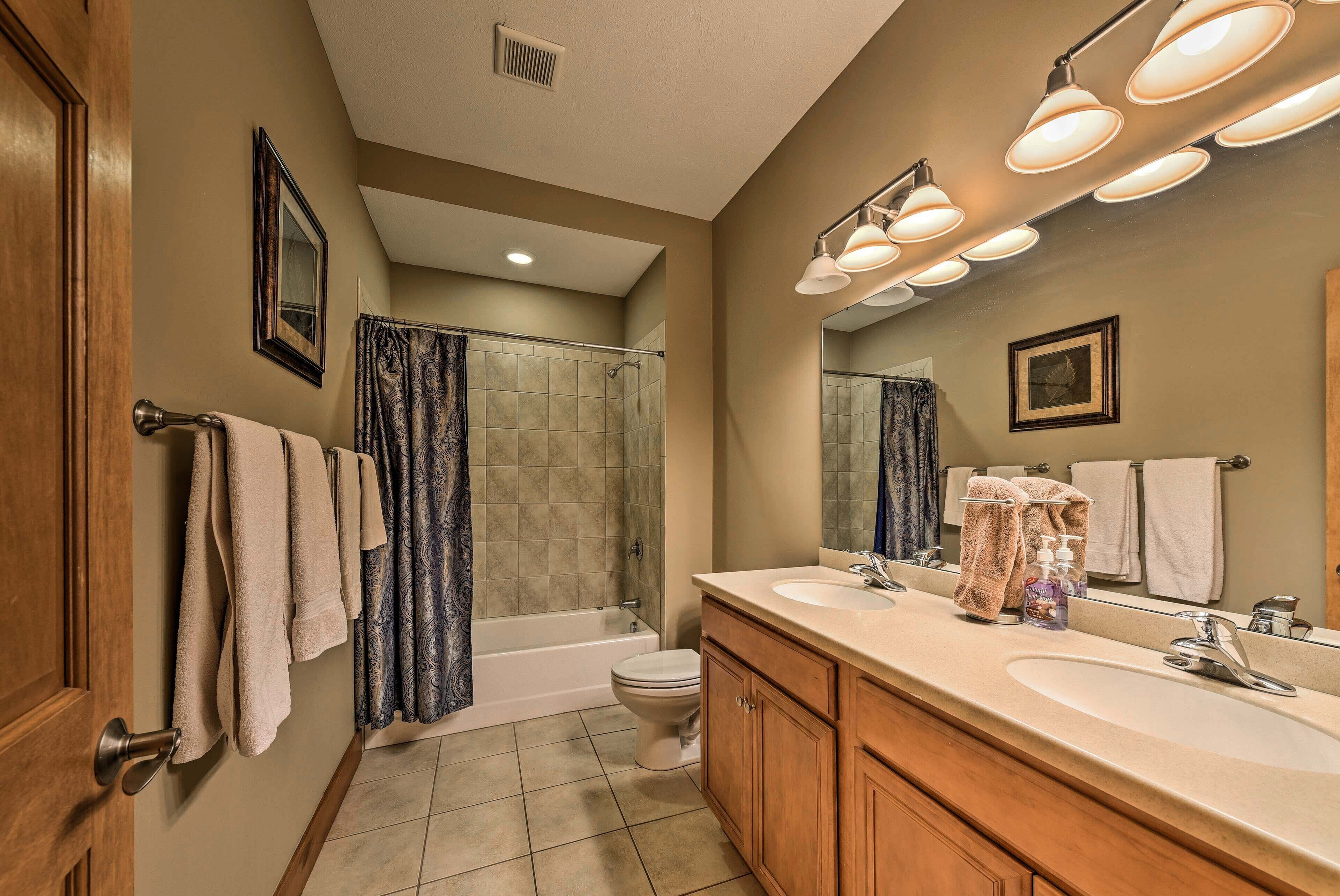 A bathroom with a bathtub, toilet, and two sinks.