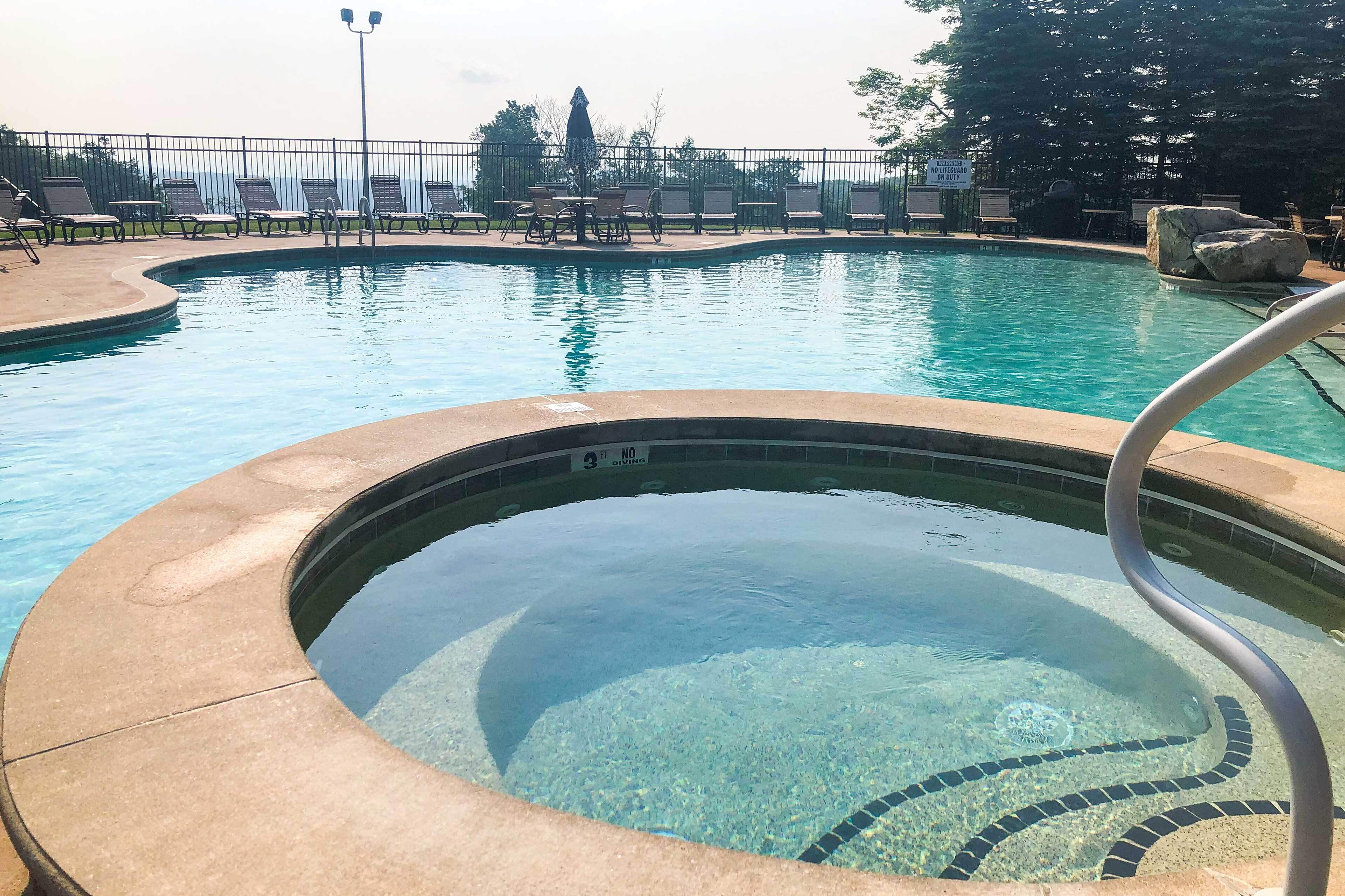 Une piscine à l’eau claire, un jacuzzi et des chaises longues.