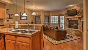 A spacious kitchen with a central island, a stone fireplace, and a cozy seating area with a leather couch. - Southwind Seven Springs Home on Ski Slopes! (Champion)
