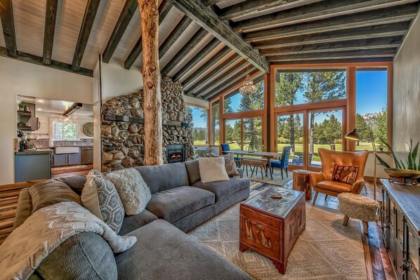 Una sala de estar acogedora con chimenea de piedra, ventanas amplias y techo rústico.