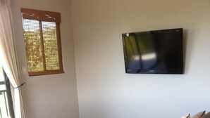 Ein Wohnzimmer mit einer Couch, einem Couchtisch und einem an der Wand befestigten Flachbildfernseher.
