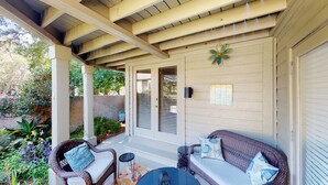 A covered porch with wicker furniture, a small table, and a lantern. - Nicely Updated First Floor Villa! (Hilton Head)