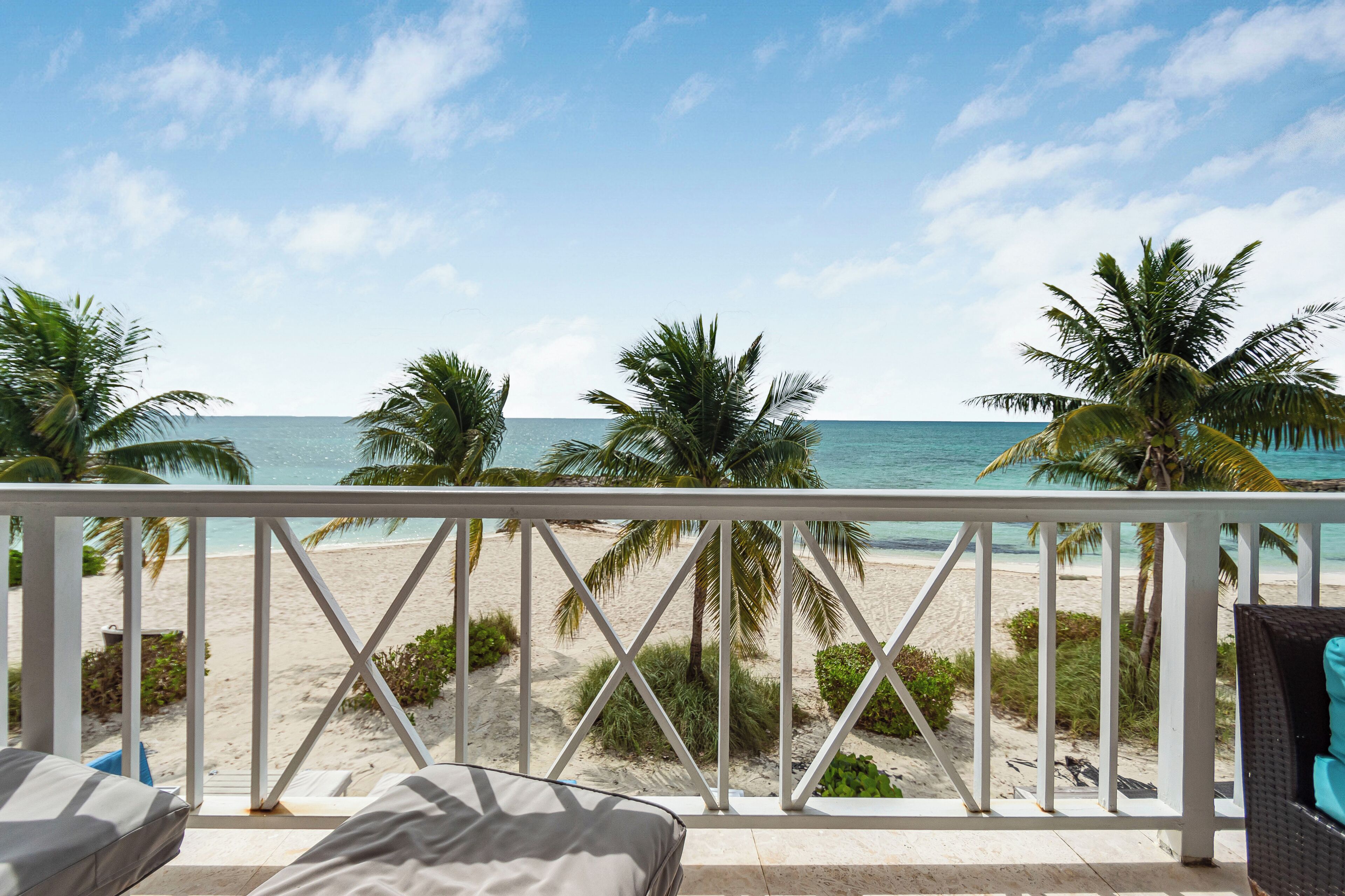 A balcony with a view of a beach and palm trees.