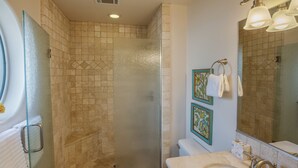 Ein Badezimmer mit Duschkabine, Toilette, Waschbecken und einem Spiegel, sowie dekorative Fliesen.
