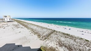 Una playa con un muelle que se adentra en el océano, arena dorada y un edificio de varios pisos.