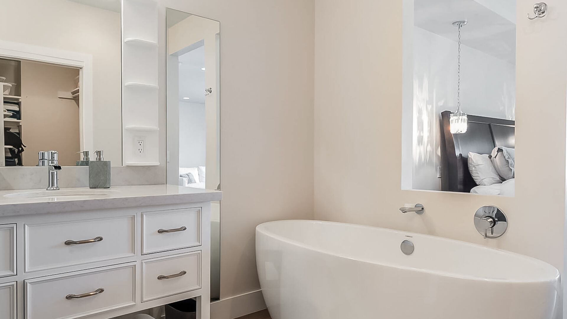 A modern bathroom with a freestanding bathtub, a large mirror, and a vanity with drawers.