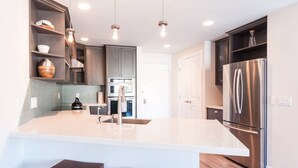 Una cocina moderna con una isla central, electrodomésticos de acero inoxidable e iluminación colgante.