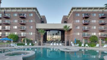 Un hotel con piscina, varios balcones y zonas de estar al aire libre.
