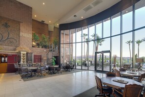 Un espace intérieur vaste et lumineux, doté d’une grande fenêtre donnant sur un paysage montagneux, et aménagé avec des tables et des chaises.