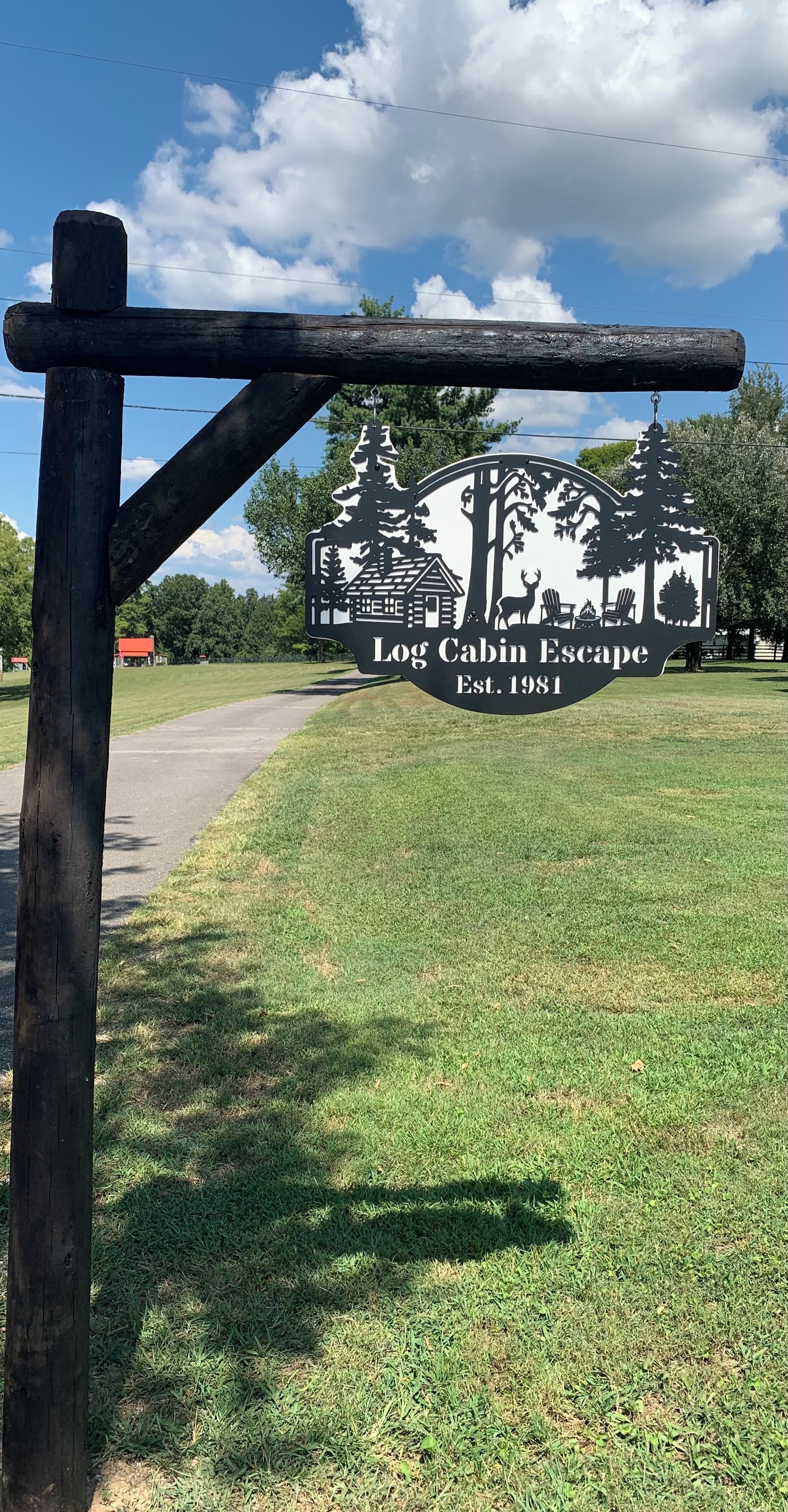 A sign for Log Cabin Escape with a rustic wooden structure and a clear sky.