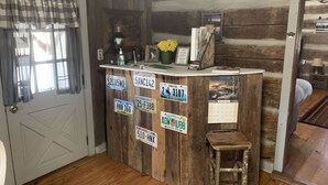 A rustic wooden counter with various license plates, a small stool, and a calendar. - Log Cabin Escape - Full Log Cabin Home (Pulaski)