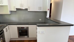 A modern kitchen with white cabinetry, a built-in oven, and a dishwasher.
