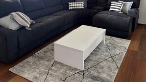 A modern living room with a sectional sofa, a white coffee table, and a ceiling fan.