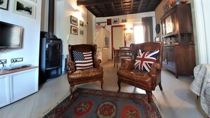 Een woonkamer met twee leren fauteuils, een open haard, een televisie en een kamerbreed tapijt met dessin.