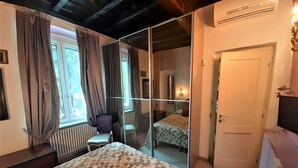 Een slaapkamer met een groot bed, een stoel, een bureau en een spiegel.