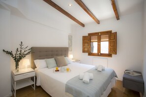 A bedroom with a large bed, bedside tables, a nightstand, a window with wooden shutters, and a small stool. - Singular Stays Quevedo I (Valencia)