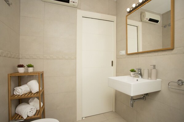 A modern bathroom with a white sink, a mirror, and a towel rack.
