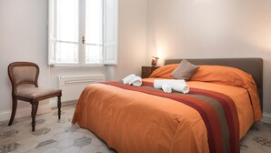 A bedroom with a bed, a chair, and a window.