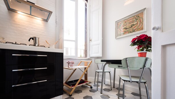 A modern kitchen with black cabinets, a gas stove, and a wooden cart.