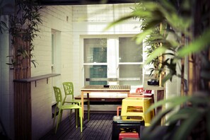 Une terrasse en bois avec une table et des chaises, entourée de plantes en pot.