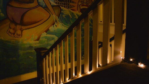 A staircase with a railing, a mural on the wall, and a window with lights. - Ritz For Backpackers (St Kilda)