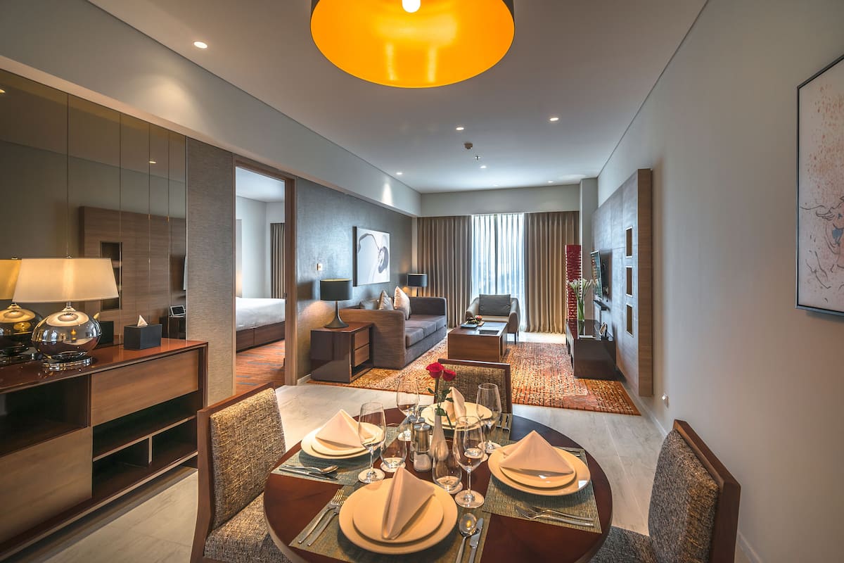 A hotel room with a dining area, a bed, a sofa, and a TV.