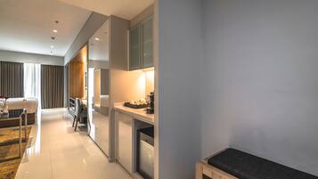 A modern hotel room with a bed, a desk, and a seating area.