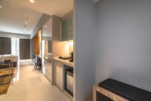 A modern hotel room with a bed, a desk, and a seating area.